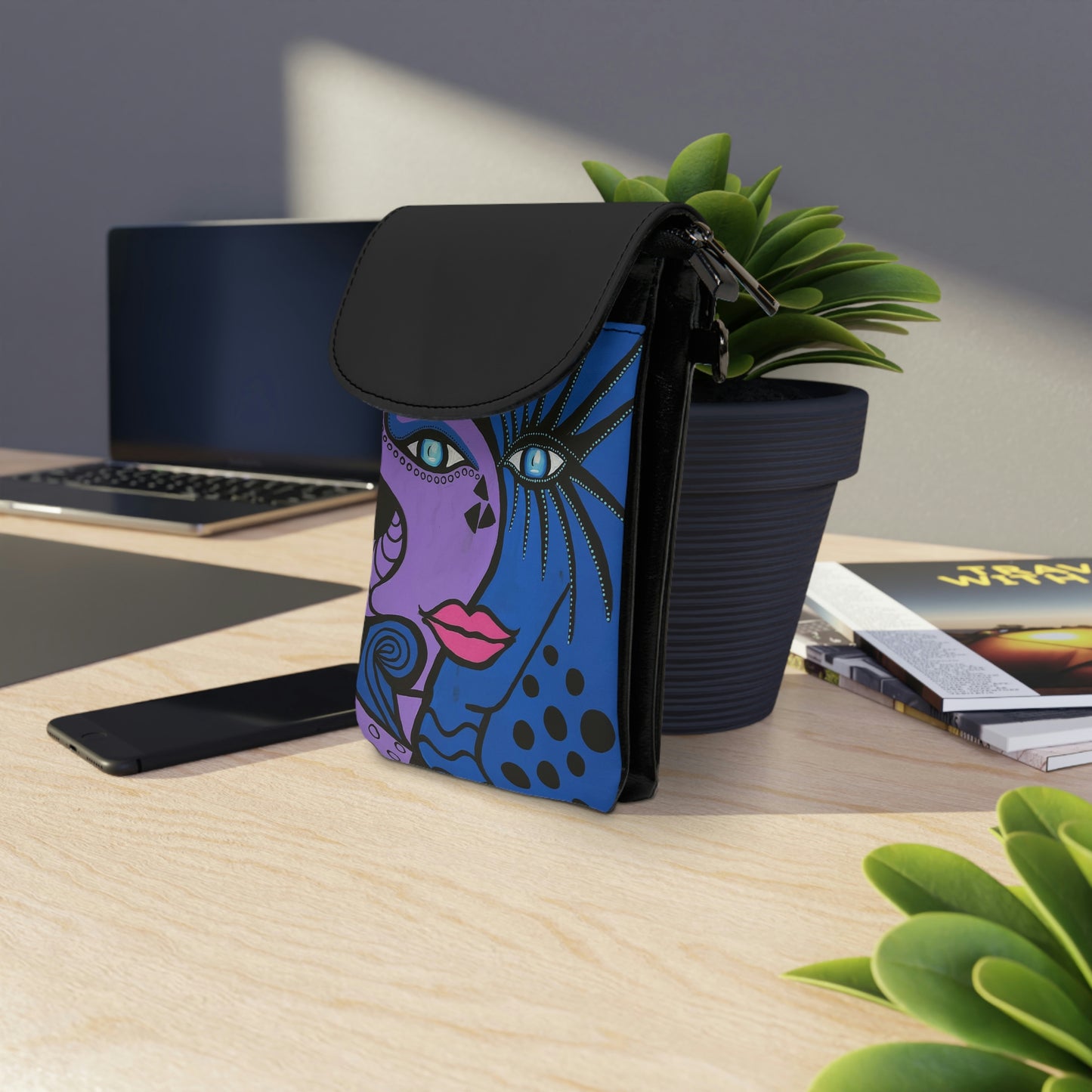 "Cobra Woman" Handytasche lehnt zum Größenvergleich an einem Blumentopf